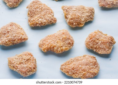 Raw Frozen Pieces Of Breaded Chicken On A Blue Background. Semi-finished Products For Homemade Nuggets