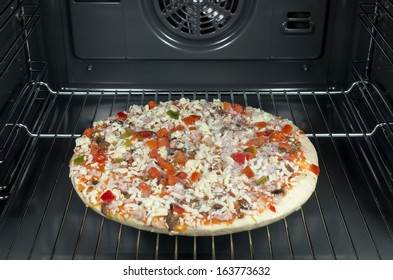 Raw And Frozen Pizza In The Oven.