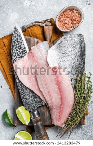 Raw Gilthead Sea bream fish fillets on a butcher cutting board. Gray background. Top view.