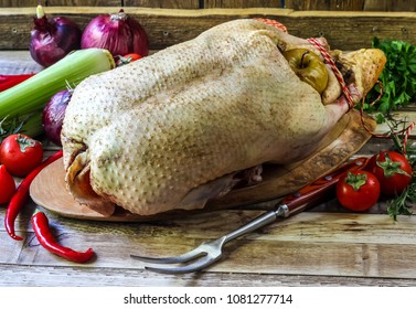 Raw goose, ready to cook, spices, apples, vegetables, greens on a wooden background. Top view. Holiday menu.