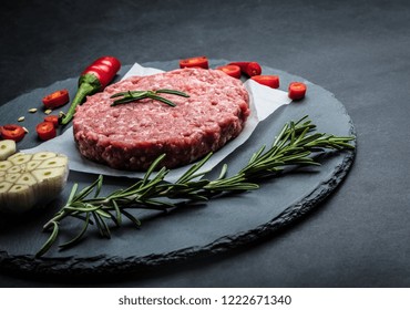 Raw Ground Beef Meat Burger Steak Cutlet With Chili, Rosemary And Garlic On Black Slate Plate For Cooking