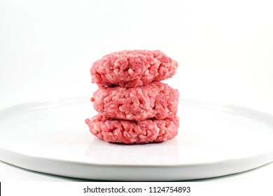 Raw Ground Beef Patties Stacked On A Plate - Isolated
