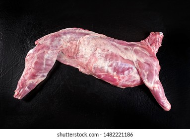 Raw Half Of Dairy Goat With Shoulder And Leg As Top View On A Black Board 