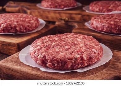 Raw hamburgers on cutting board with wood pile background - Close-up