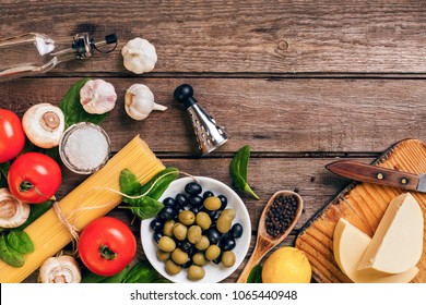 Raw ingredients for the preparation of Italian pasta, spaghetti, basil, tomatoes, olives and olive oil on wooden background. Top view. Copy space. - Shutterstock ID 1065440948