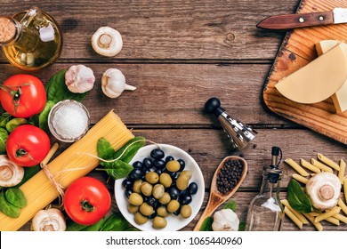 Raw ingredients for the preparation of Italian pasta, spaghetti, basil, tomatoes, olives and olive oil on wooden background. Top view. Copy space. - Shutterstock ID 1065440960