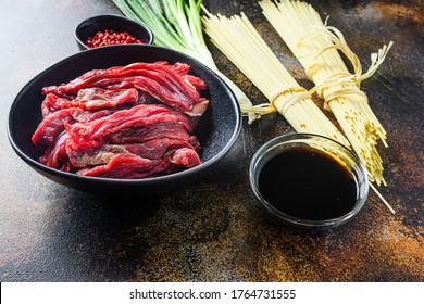 Raw Ingredients For Stir Fry Chinese Noodles With Vegetables And Beef In Black Bowl. On Old Rustic Table. Side View.