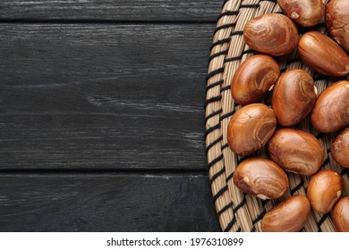 Raw jackfruit seeds on black wooden table, flat lay. Space for text