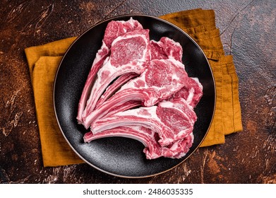 Raw lamb chops, fresh mutton meat cutlets on a ribs. Dark background. Top view. - Powered by Shutterstock