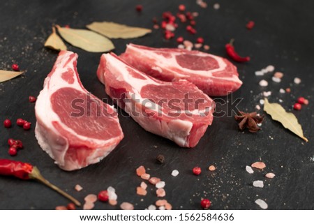 Raw lamb chops or mutton cuts with salt and spices on black stone background. Fresh sheep ribs cutlet on bone closeup Stock photo © 