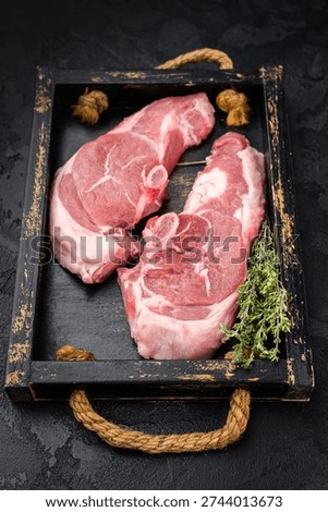 Raw lamb chump chops with bone served on rustic wooden tray with fresh thyme, premium sirloin saddle meat ready for grilling, roasting or gourmet cooking