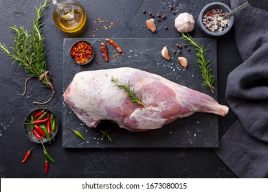 Raw lamb leg with spices and herbs on marble cutting board. Dark background. Top view. - Shutterstock ID 1673080015