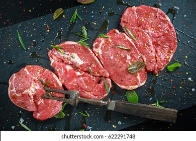 Raw Lamb leg steaks on stone chopping board with vintage fork served with sea salt and chillie flakes, rosemary and mint - Powered by Shutterstock