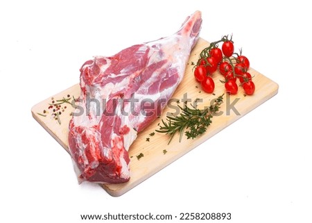 raw lamb leg with vegetables, loin on the bone with herbs, meat shoulder blade on a wooden cutting board, on a white isolated background