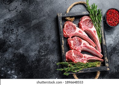 Raw lamb meat chops steaks in a wooden tray. Black background. Top view. Copy space. - Shutterstock ID 1896648553