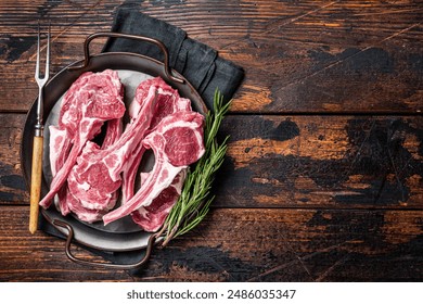 Raw lamb mutton chop steaks, fresh meat cutlets on butcher table. Black background. Top view. Copy space.