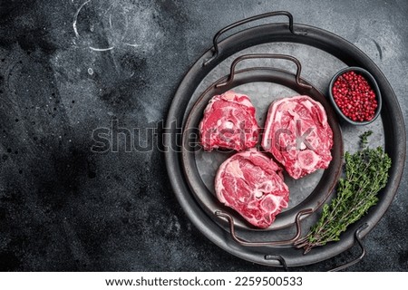 Raw lamb neck meat with bone on a steel tray. Black background. Top view. Copy space.