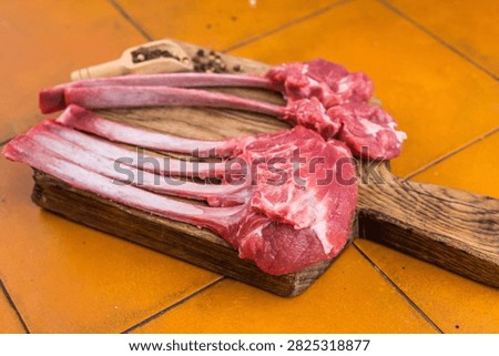 Raw lamb rack ribs and chops steaks on wooden board terracotta tile background top view butcher meat with copy space.