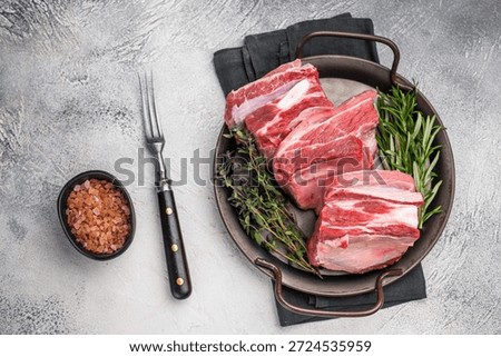 Raw lamb Riblets, fresh mutton meat with rib bone. grey background. top view.