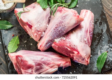 Raw lamb shanks with salt and pepper on stone tray on rustic wooden table, selective focus - Powered by Shutterstock