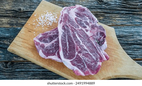 Raw lamb shoulder chops ready for cooking on a wooden cutting board - Powered by Shutterstock