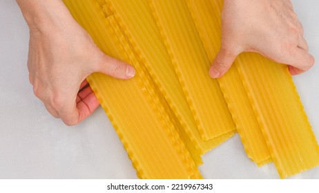 Raw Lasagna Noodles Close Up On Kitchen Table, View From Above, Woman Hands