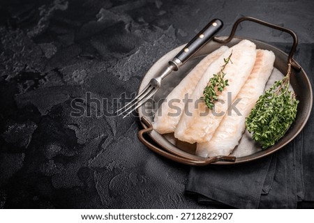 Raw Loin cod fish fillets ready for cooking whitefish in stell tray. black background. top view.