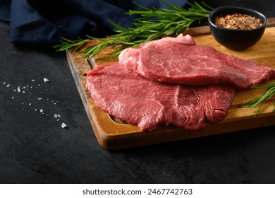 Raw marbled steak with rosemary sprig and salt on black background. Copy space. Close up. - Powered by Shutterstock