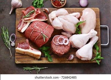 raw meat assortment - beef, lamb, chicken on a wooden board