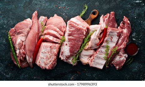 Raw meat background. Meat on a black stone background with spices and herbs. Top view. Rustic style.