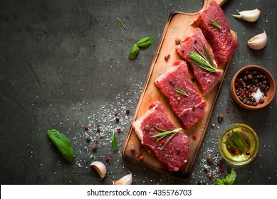 Raw meat. Raw beef steak on a cutting board with rosemary and spices.