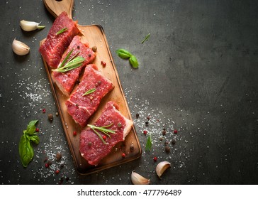Raw meat. Raw beef steak on a cutting board with rosemary and spices. - Shutterstock ID 477796489