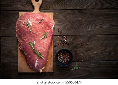 Raw meat. Raw beef tenderloin on a cutting board with rosemary and spices.