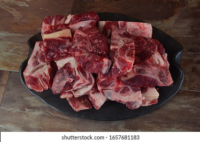 Raw Meat With Bone On Clay Plate And Brown Stone Background.Raw Meat With Beef Bone. Beef Bone Selection For Soup