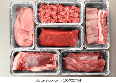 Raw meat in foil containers on light background - Shutterstock ID 1054027484