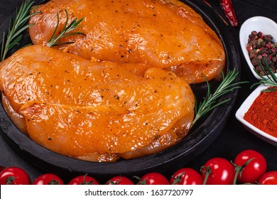 Raw meat in the marinade.Marinated Chicken Breast with spices and rosemary on a black plate.Sottilissime