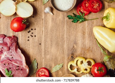 Raw meat on a wooden chopping board with fresh organic vegetables, onion, garlic, spices, peppercorn, salt, tomatoes and parsley for cooking. Kitchen ideas. Lunch, dinner - Powered by Shutterstock