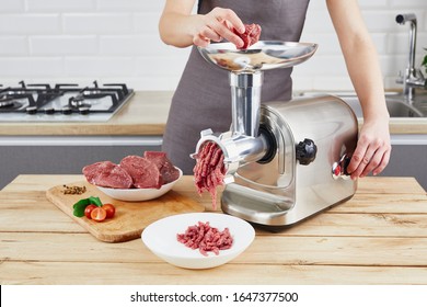 Raw meat. The process of preparing forcemeat by means of a meat grinder. Female hands use meat chopper at kitchen.