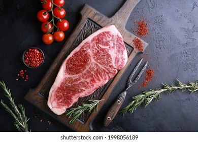 Raw Meat Steak. Japanese Marble Wagyu Meat On A Dark Wooden Board With Spices, Rosemary And Fresh Cherry Tomatoes. Background Image, Copy Space. Top View, Flatlay