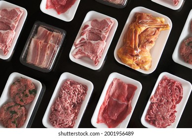 Raw meat in trays on black background - Powered by Shutterstock