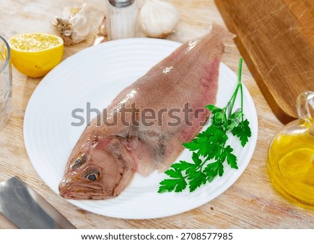 Raw megrim fish served on plate with parsley and fresh lemon