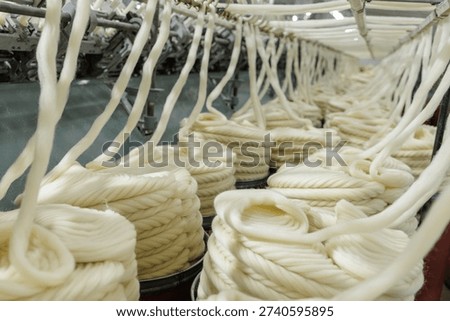Raw merino wool yarn processed and coiled in automated textile factory line, ideal for fabric production, apparel manufacturing, and supply chain visuals.