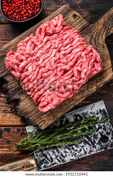 Raw mince beef,\
ground meat with herbs and spices on a wooden cutting board. Dark\
wooden background. Top\
view.
