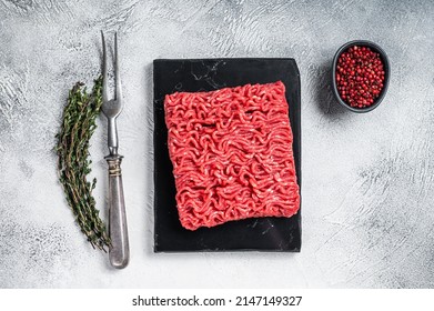 Raw mince Minced beef, ground meat with thyme and pepper. White background. Top view.