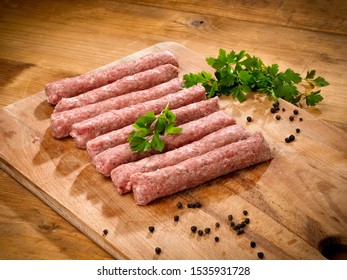 Raw minced meat cevapi on a wooden board, close up