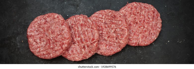 Raw Minced Steak Burgers From Beef And Pork Meat On Black Background, Overhead View. Raw Ground Beef, Round Patties For Cooking Homemade Burger On BBQ Grill, Top View