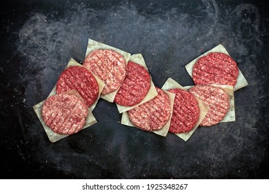 Raw Minced Steak Burgers In Row From Beef And Pork Meat On Black Background, Overhead View. Raw Ground Beef, Round Patties For Cooking Homemade Burger On BBQ Grill, Top View