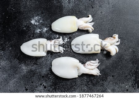 Raw mini cuttlefish on the table. Black background. Top view
