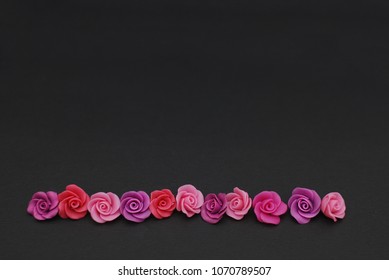Raw Mix of pink and Peach Fake Plastic Mini rosess Flowers Black Background copy space. Craft, Art, Hobby concept.