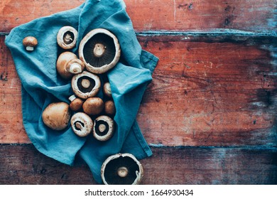 Raw Mushrooms On A Wooden Background With A Blue Linen Napkin, Overhead View (toned Image)